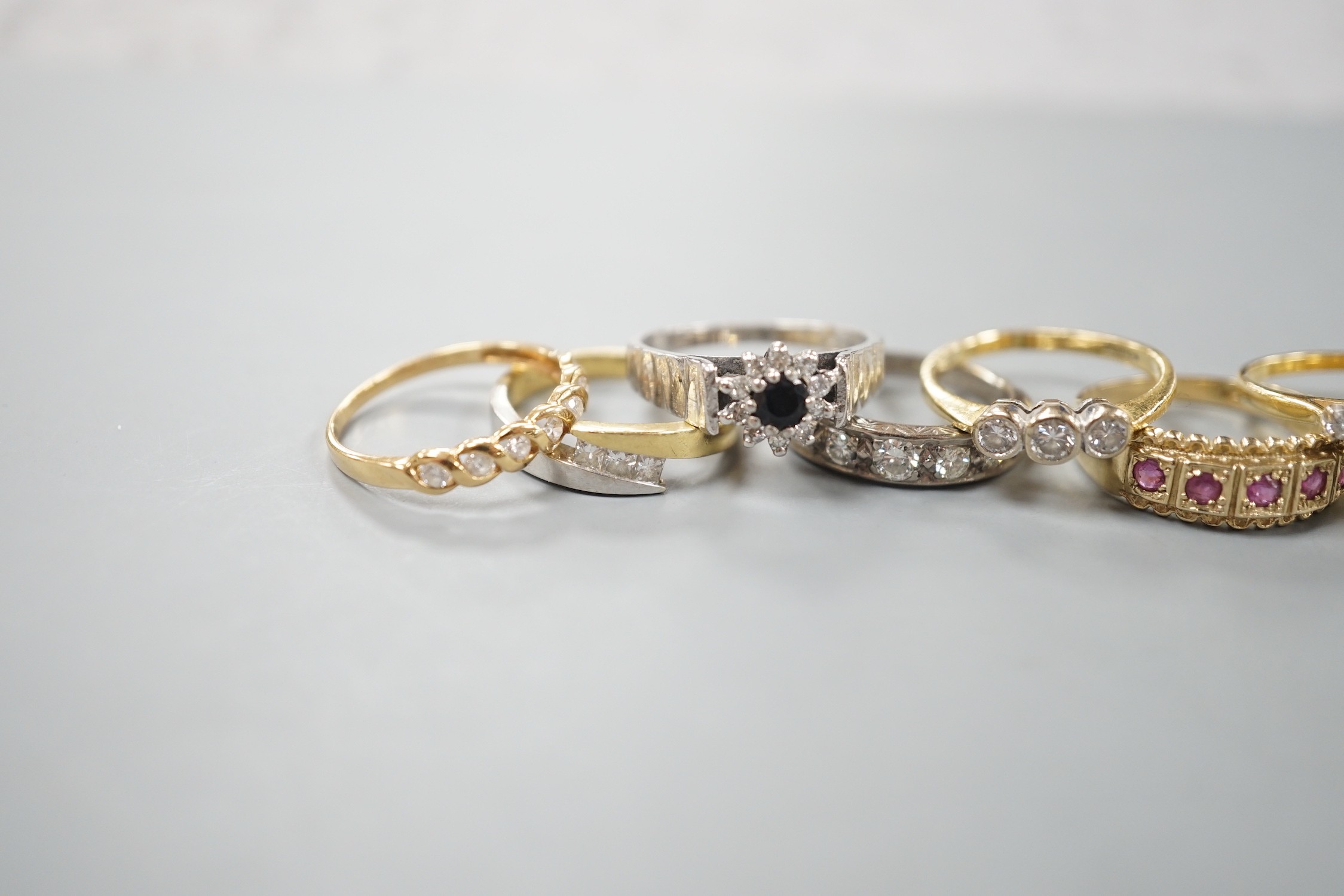 Seven assorted mainly modern 18ct gold or 750 yellow metal and gem set dress rings including emerald and diamond and diamond half eternity, gross weight 26 grams and one 9ct gold and gem set ring, gross 2.9 grams.
